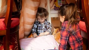 Portret van het leuke peuterjongen spelen met oudere zuster in tent bij slaapkamer royalty-vrije stock foto's Portret van het leuke peuterjongen spelen met oudere zuster in tent bij slaapkamer royalty-vrije stock foto's