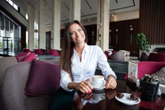 Portret van jonge schitterende vrouwelijke het drinken thee en het kijken met glimlach uit het venster van de koffiewinkel terwij stock afbeeldingen Portret van jonge schitterende vrouwelijke het drinken thee en het kijken met glimlach uit het venster van de koffiewinkel terwij stock afbeeldingen