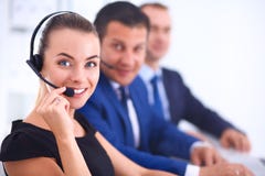 Portret van mooie bedrijfsvrouw die in hoofdtelefoons met collega's op achtergrond glimlachen Royalty-vrije Stock Afbeeldingen Portret van mooie bedrijfsvrouw die in hoofdtelefoons met collega's op achtergrond glimlachen Royalty-vrije Stock Afbeeldingen