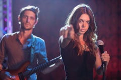 Portret van vrouwelijke zanger met mannelijke gitarist die bij nachtclub presteren stock afbeeldingen Portret van vrouwelijke zanger met mannelijke gitarist die bij nachtclub presteren stock afbeeldingen