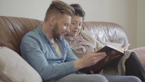Portret ładna stara kobieta i dorosłego wnuk siedzi w domu oglądający stare fotografie w dużym albumu fotograficznym Rodzina pami zbiory Portret ładna stara kobieta i dorosłego wnuk siedzi w domu oglądający stare fotografie w dużym albumu fotograficznym Rodzina pami zbiory