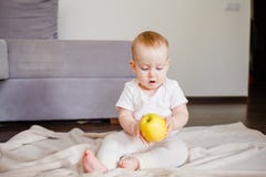 Portret śliczny małe dziecko z jeden żółtym jabłkiem, siedzi na podłodze Dziewczynka 9 miesięcy stary mienie owoc obrazy royalty free Portret śliczny małe dziecko z jeden żółtym jabłkiem, siedzi na podłodze Dziewczynka 9 miesięcy stary mienie owoc obrazy royalty free