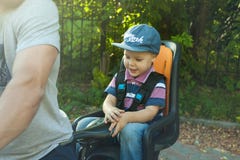 Portret Śliczny mały caucasian 3 lat berbecia chłopiec dziecko jest ubranym nakrętkę w siedzenie bicyklu za ojcem, outdoors fotografia stock Portret Śliczny mały caucasian 3 lat berbecia chłopiec dziecko jest ubranym nakrętkę w siedzenie bicyklu za ojcem, outdoors fotografia stock