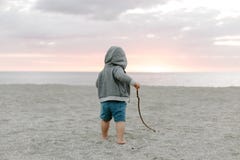 Portret Śliczny Mały chłopiec dziecko Bawić się i Bada w piasku przy plażą Podczas zmierzchu Outside na wakacje w Hoodie zdjęcie royalty free Portret Śliczny Mały chłopiec dziecko Bawić się i Bada w piasku przy plażą Podczas zmierzchu Outside na wakacje w Hoodie zdjęcie royalty free