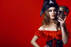 Porträt der herrlichen sexy Frau mit provozierendem Make-up im Piratenkostüm, das Schädelmaske nahe bei ihrem Gesicht hält lizenzfreies stockbild Porträt der herrlichen sexy Frau mit provozierendem Make-up im Piratenkostüm, das Schädelmaske nahe bei ihrem Gesicht hält lizenzfreies stockbild