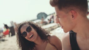 Porträt der jungen Frau im Bikini, der mit Freunden auf dem Strand und dem Lächeln sitzt stock video footage Porträt der jungen Frau im Bikini, der mit Freunden auf dem Strand und dem Lächeln sitzt stock video footage