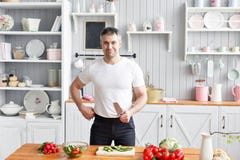 Porträt des hübschen lächelnden Mannes, der Gemüse in der Küche hackt Das Konzept von umweltfreundlichen Produkten für das Kochen stockbild Porträt des hübschen lächelnden Mannes, der Gemüse in der Küche hackt Das Konzept von umweltfreundlichen Produkten für das Kochen stockbild