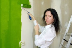 Porträt einer lächelnden hübschen jungen Frau malt grüne Innenwand mit Rolle in einem neuen Haus und zeigt auf ihre Arbeit lizenzfreie stockfotografie Porträt einer lächelnden hübschen jungen Frau malt grüne Innenwand mit Rolle in einem neuen Haus und zeigt auf ihre Arbeit lizenzfreie stockfotografie
