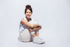 Porträt einer zufälligen glücklichen Frau, die auf dem Boden auf weißem Hintergrund sitzt stockfotografie Porträt einer zufälligen glücklichen Frau, die auf dem Boden auf weißem Hintergrund sitzt stockfotografie