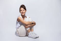 Porträt einer zufälligen glücklichen Frau, die auf dem Boden auf weißem Hintergrund sitzt stockfotografie Porträt einer zufälligen glücklichen Frau, die auf dem Boden auf weißem Hintergrund sitzt stockfotografie