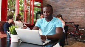 Porträt eines glücklichen Afroamerikanerunternehmers, der Computer im Büro anzeigt Lizenzfreie Stockbilder Porträt eines glücklichen Afroamerikanerunternehmers, der Computer im Büro anzeigt Lizenzfreie Stockbilder