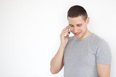 Porträt eines netten, positiven, attraktiven Kerls mit Stoppel in einem grauen T-Shirt, sprechend am Telefon auf einem grauen Hin lizenzfreies stockfoto Porträt eines netten, positiven, attraktiven Kerls mit Stoppel in einem grauen T-Shirt, sprechend am Telefon auf einem grauen Hin lizenzfreies stockfoto