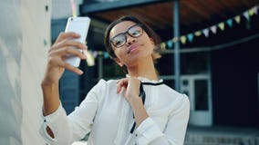 Porträt junger Afroamerikanerdame, die draußen selfie mit Smartphone nimmt stock footage Porträt junger Afroamerikanerdame, die draußen selfie mit Smartphone nimmt stock footage