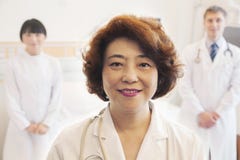 Porträt von drei lächelnden Doktoren, Ärztin an der Front lizenzfreies stockbild Porträt von drei lächelnden Doktoren, Ärztin an der Front lizenzfreies stockbild