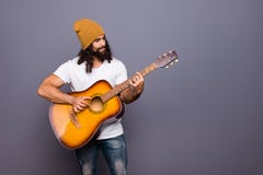 Porträt von seinem schlug er der nette hübsche attraktive nette überzeugte gewellt-haarige Kerl, der Gitarre spielt, Poprockkompo lizenzfreie stockbilder Porträt von seinem schlug er der nette hübsche attraktive nette überzeugte gewellt-haarige Kerl, der Gitarre spielt, Poprockkompo lizenzfreie stockbilder