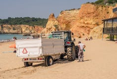 PORTUGALIA, KWIECIEŃ - 2017: Śmieciarski poborca na plaży w Kwietniu 17, 2017, lokalizować w Portimao, Portugalia Praia da Rocha obraz royalty free PORTUGALIA, KWIECIEŃ - 2017: Śmieciarski poborca na plaży w Kwietniu 17, 2017, lokalizować w Portimao, Portugalia Praia da Rocha obraz royalty free