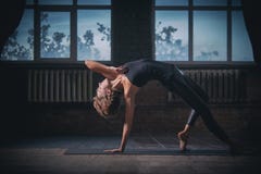Pose selvagem da coisa do asana desportivo bonito da ioga das práticas da mulher do yogini do ajuste no salão escuro Imagem de Stock Royalty Free Pose selvagem da coisa do asana desportivo bonito da ioga das práticas da mulher do yogini do ajuste no salão escuro Imagem de Stock Royalty Free