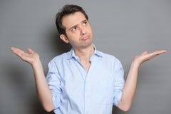 Posi??o vestindo da camisa do homem confuso e shrugging sobre o fundo cinzento imagens de stock royalty free Posi??o vestindo da camisa do homem confuso e shrugging sobre o fundo cinzento imagens de stock royalty free