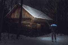Position de photographe d'homme devant le cottage abadoned et rampant dans la forêt en hiver L'homme sur l'expédition shinning av images stock Position de photographe d'homme devant le cottage abadoned et rampant dans la forêt en hiver L'homme sur l'expédition shinning av images stock