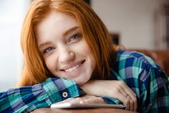 Positive Frau mit dem roten Haar hörend Musik vom Mobiltelefon stockfotografie Positive Frau mit dem roten Haar hörend Musik vom Mobiltelefon stockfotografie