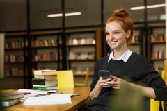 Positive red haired teenage girl studying at the table stock photos Positive red haired teenage girl studying at the table stock photos