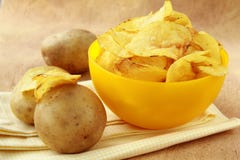 Potato chips in a yellow cup, and potato Stock Photography Potato chips in a yellow cup, and potato Stock Photography
