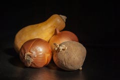 Potatoes with sprouts in the foreground onions and pumpkins on a black background royalty free stock photo Potatoes with sprouts in the foreground onions and pumpkins on a black background royalty free stock photo