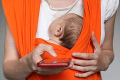 Poti la madre con il bambino in smartphone della tenuta dell'imbracatura immagini stock libere da diritti Poti la madre con il bambino in smartphone della tenuta dell'imbracatura immagini stock libere da diritti