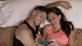 Potomstwa dobierają się obsiadanie w łóżku ogląda wideo na smartphone wyraża ich zdziwioną reakcję o zawartości zbiory Potomstwa dobierają się obsiadanie w łóżku ogląda wideo na smartphone wyraża ich zdziwioną reakcję o zawartości zbiory