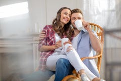 Potomstwa dobierają się siedzącego obejmowanie i pić herbata w kołysać krzesła obrazy stock Potomstwa dobierają się siedzącego obejmowanie i pić herbata w kołysać krzesła obrazy stock