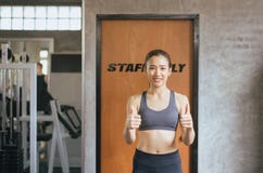 Pouce asiatique convenable de femme et détendre après le stage de formation dans le gymnase, le concept sain et le mode de vie, f photos stock Pouce asiatique convenable de femme et détendre après le stage de formation dans le gymnase, le concept sain et le mode de vie, f photos stock