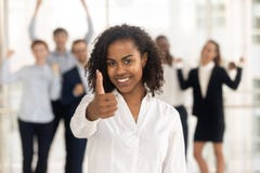 Pouces de représentation femelles africains satisfaisants vers le haut des employés heureux à l'arrière-plan image libre de droits Pouces de représentation femelles africains satisfaisants vers le haut des employés heureux à l'arrière-plan image libre de droits