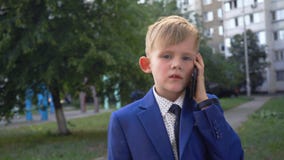 Pouco menino bonito em negociações de terno e de laço de negócio no telefone filme Pouco menino bonito em negociações de terno e de laço de negócio no telefone filme