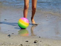 Pouco pés pequenos da criança na água em Sandy Beach Relaxing e estar com a bola colorida durante férias de verão fotografia de stock Pouco pés pequenos da criança na água em Sandy Beach Relaxing e estar com a bola colorida durante férias de verão fotografia de stock