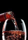 Pouring Rose Wine From Bottle To Glass On Black Stock Photography