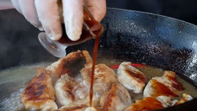 Pouring sauce over fried dumplings in pan