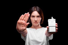 Poważna dziewczyna z paczką papierosy na czarnym tle Młoda kobieta pokazuje przerwa znaka Zdrowy Styl życia obrazy stock Poważna dziewczyna z paczką papierosy na czarnym tle Młoda kobieta pokazuje przerwa znaka Zdrowy Styl życia obrazy stock