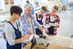 Poważny cieśla piłuje drewnianą deskę przy woodworking klasą zdjęcie stock Poważny cieśla piłuje drewnianą deskę przy woodworking klasą zdjęcie stock