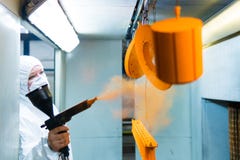 Powder coating of metal parts. A woman in a protective suit sprays powder paint from a gun on metal products stock photos Powder coating of metal parts. A woman in a protective suit sprays powder paint from a gun on metal products stock photos