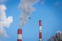 The power station with two smoke stacks and black bird flying air pollution. On blue sky background Stock Photos The power station with two smoke stacks and black bird flying air pollution. On blue sky background Stock Photos