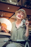 Pozytywna ładna kobieta używa pięknego fan zdjęcie stock Pozytywna ładna kobieta używa pięknego fan zdjęcie stock