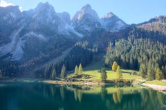 Prachtig de herfstlandschap van Meer Gosausee met ruwe rotsachtige bergpieken op de achtergrond en mooie bezinningen over water Stock Foto Prachtig de herfstlandschap van Meer Gosausee met ruwe rotsachtige bergpieken op de achtergrond en mooie bezinningen over water Stock Foto