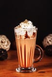 Prachtig ontworpen latte macchiatokoffie met slagroom en bestrooid met verpletterde halva, op een donkere achtergrond royalty-vrije stock afbeelding Prachtig ontworpen latte macchiatokoffie met slagroom en bestrooid met verpletterde halva, op een donkere achtergrond royalty-vrije stock afbeelding