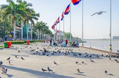 Preah Sisowath Quay et le parc de Royal Palace avec des drapeaux, des pigeons et des personnes locales dans Phnom Penh, Cambodge image stock Preah Sisowath Quay et le parc de Royal Palace avec des drapeaux, des pigeons et des personnes locales dans Phnom Penh, Cambodge image stock