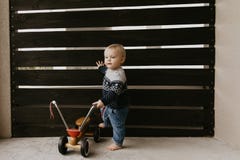 Precious Adorable Cute Little Blonde Baby Toddler Boy Kid Playing Outside On Wooden Toy Bicycle Scooter Mobile Smiling At The Came Stock Photos Precious Adorable Cute Little Blonde Baby Toddler Boy Kid Playing Outside On Wooden Toy Bicycle Scooter Mobile Smiling At The Came Stock Photos