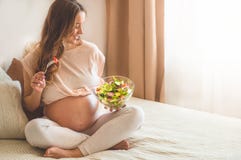 Pregnancy and healthy organic nutrition. Pregnant woman enjoying fresh vegetable salad in bed, free space royalty free stock photo Pregnancy and healthy organic nutrition. Pregnant woman enjoying fresh vegetable salad in bed, free space royalty free stock photo