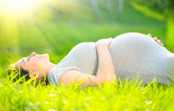 Pregnant middle aged woman touching her belly lying on green grass, enjoying nature. Pregnancy concept stock images Pregnant middle aged woman touching her belly lying on green grass, enjoying nature. Pregnancy concept stock images