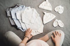 Pregnant unrecognizable woman sitting with baby clothes. Top view stock photos Pregnant unrecognizable woman sitting with baby clothes. Top view stock photos