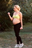 Pregnant woman exercising with dumbbells outdoor stock photo Pregnant woman exercising with dumbbells outdoor stock photo
