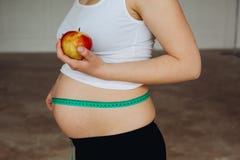 Pregnant woman measuring her big pregnant belly with measuring families. Mom Is Expecting A Baby. The concept of Royalty Free Stock Photo Pregnant woman measuring her big pregnant belly with measuring families. Mom Is Expecting A Baby. The concept of Royalty Free Stock Photo
